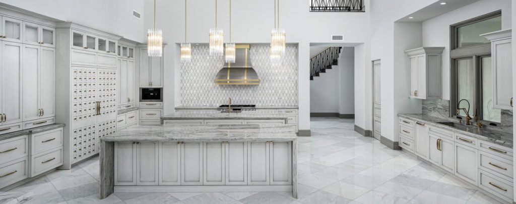 A large kitchen with white cabinets and marble counter tops.