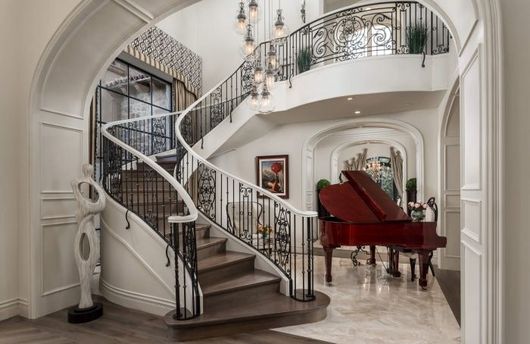 There is a grand piano in the middle of the room next to the stairs.