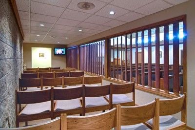 A row of wooden chairs in a room with a television on the wall