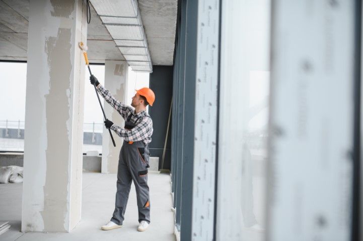 A man is painting a wall with a paint roller.
