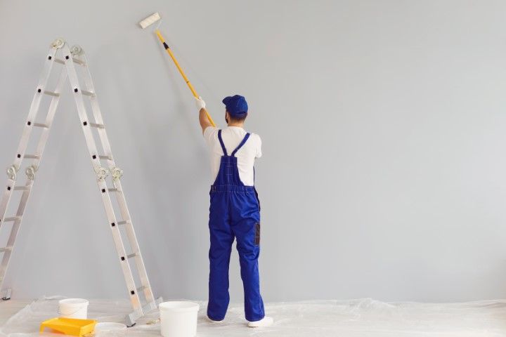 A man is painting a wall with a paint roller.