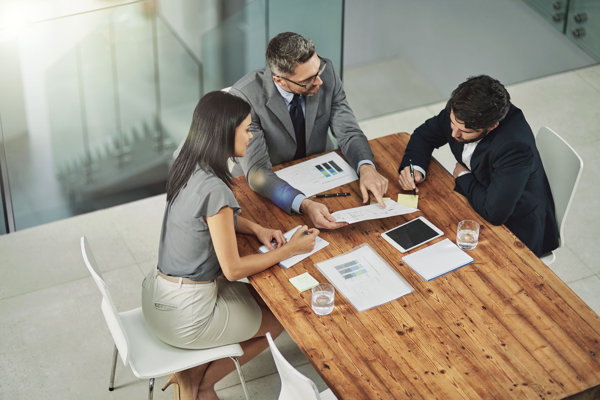 Three People in Suits at a Wooden Table Reviewing Documents — Dwyer Law Group in Surfers Paradise, QLD