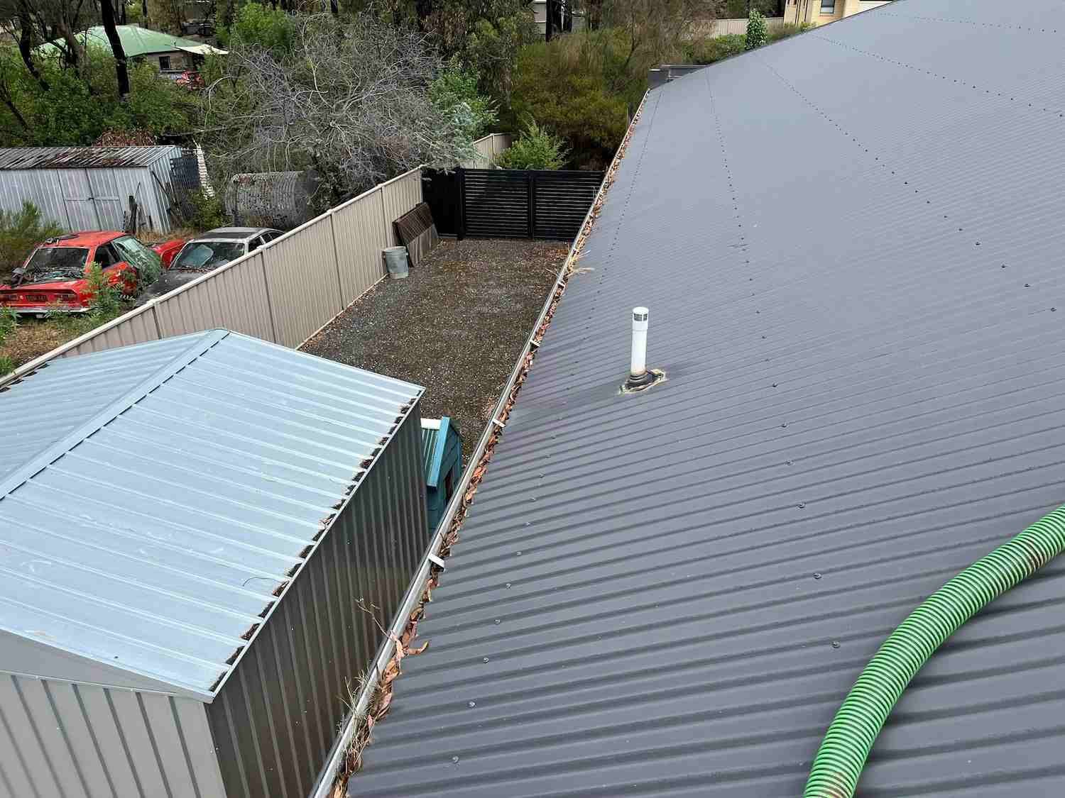 A Green Hose is Hanging From the Roof of a House — GUTTER MUNCHER In Bendigo, VIC