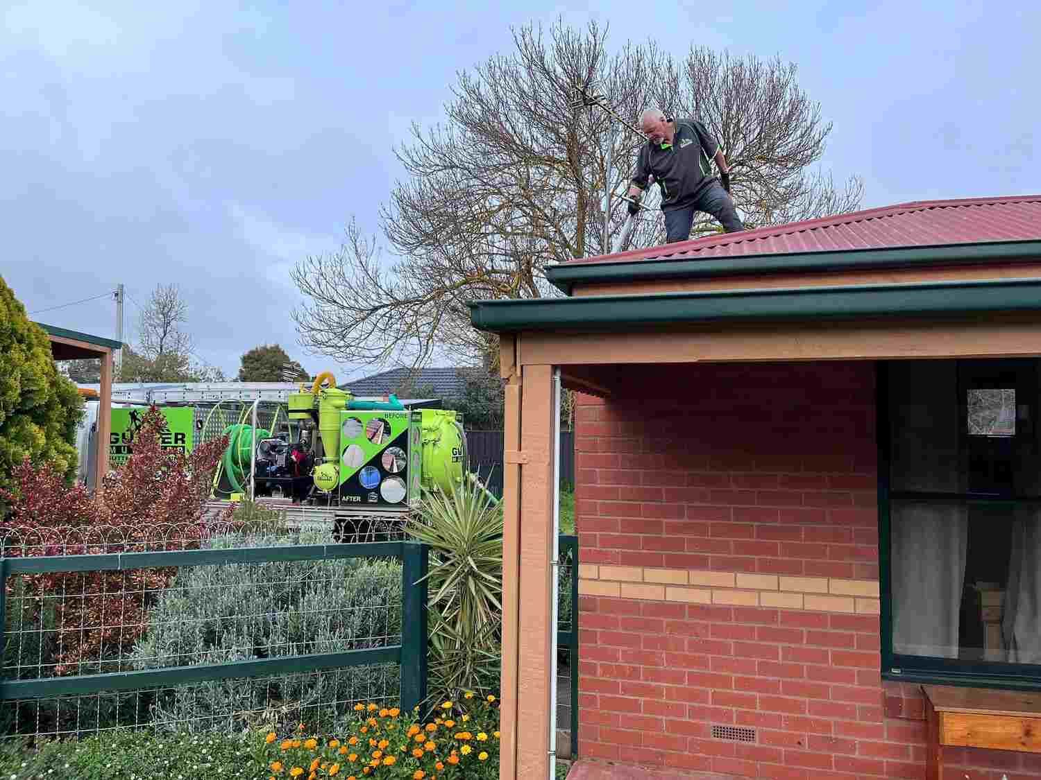 A Man is Standing on the Roof of a Brick House — GUTTER MUNCHER In Bendigo, VIC