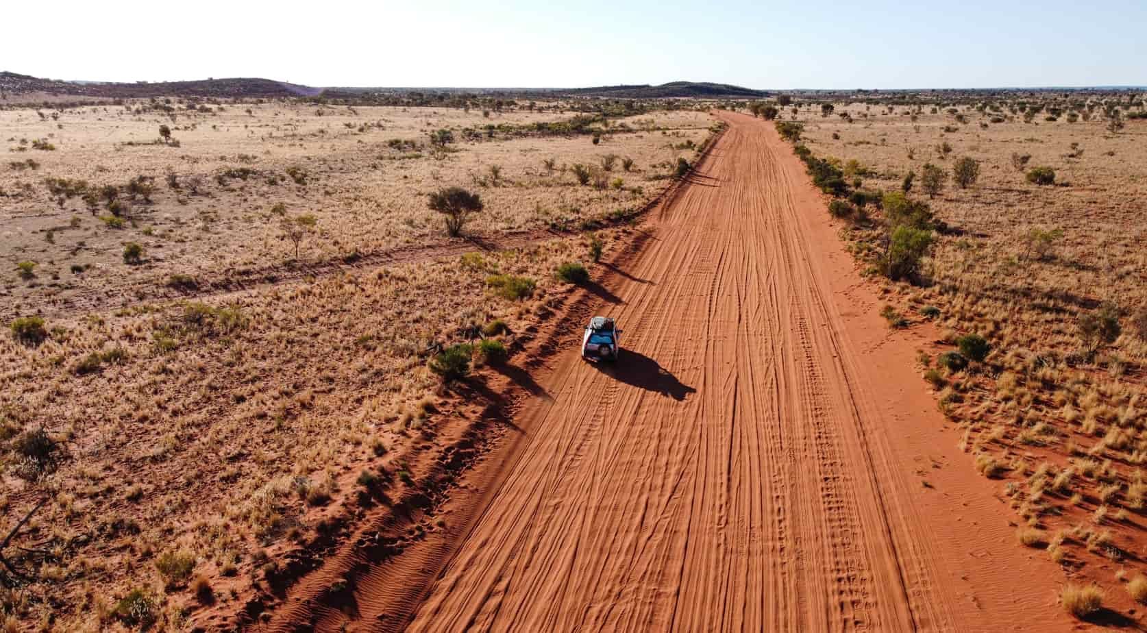 An Aerial View of a Car Driving Down a Dirt Road in the Desert — Red Central Towing & Recovery In Alice Springs, NT