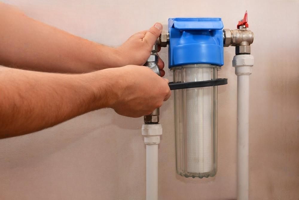 A person is installing a water filter on a pipe.