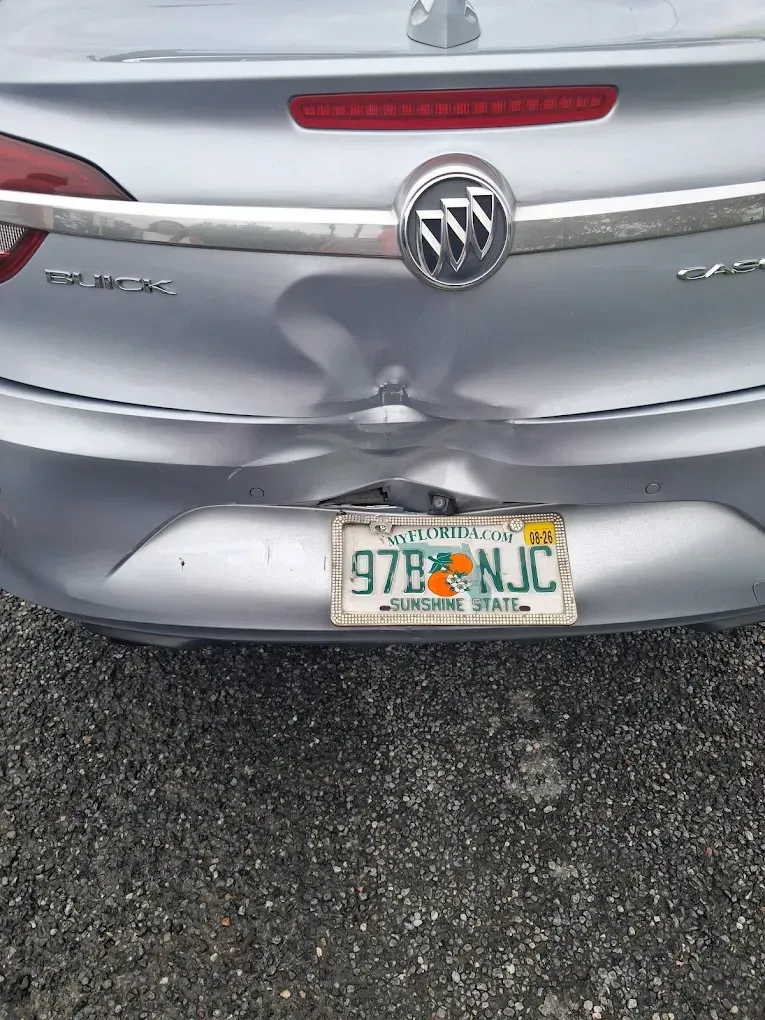 Silver Buick with rear-end damage, license plate visible.