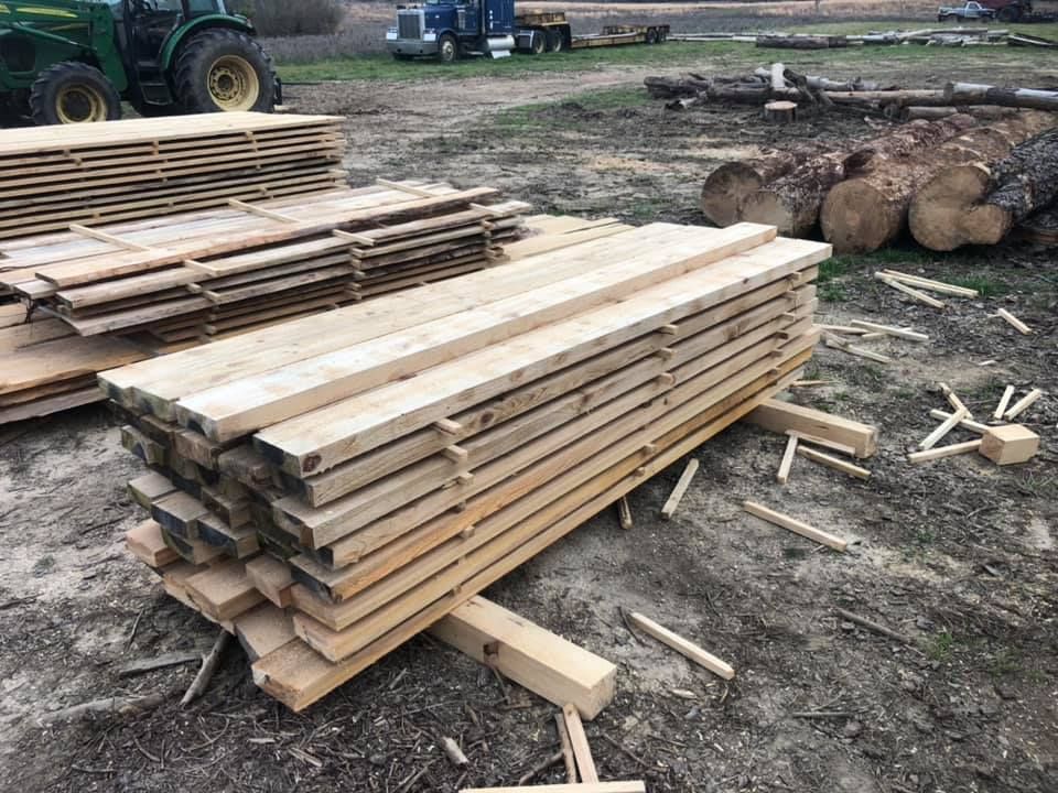 A pile of wood is sitting on the ground next to a tractor.