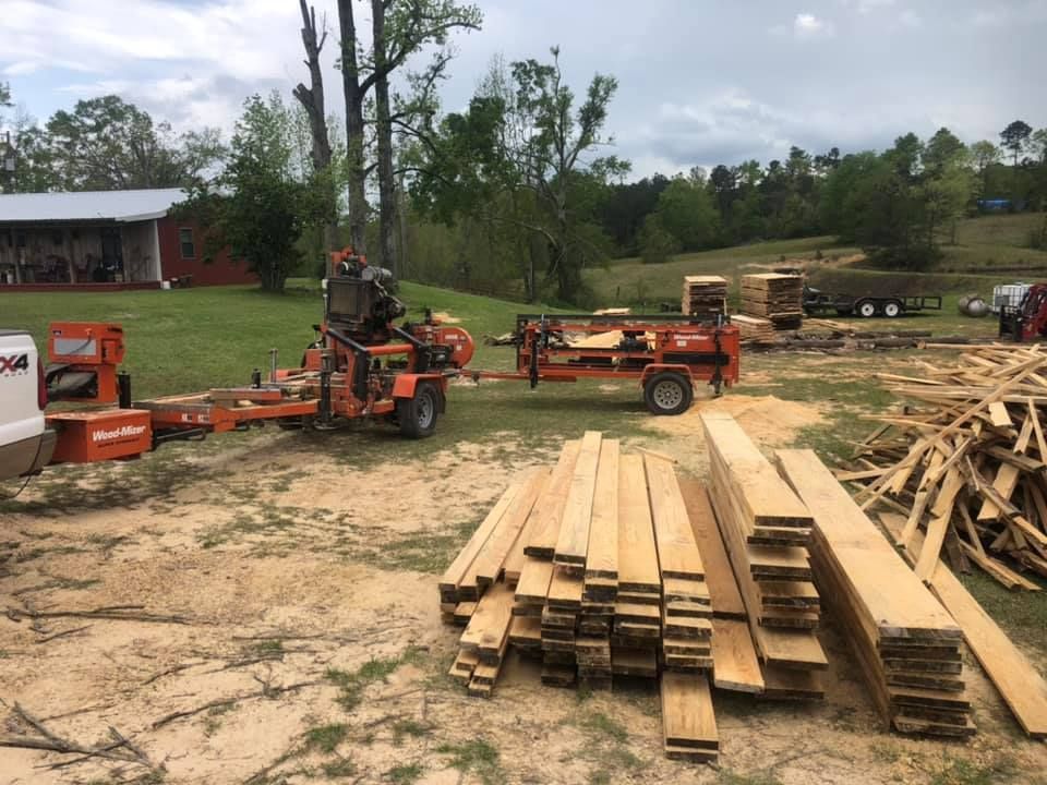 A pile of wood is sitting on the ground next to a machine.