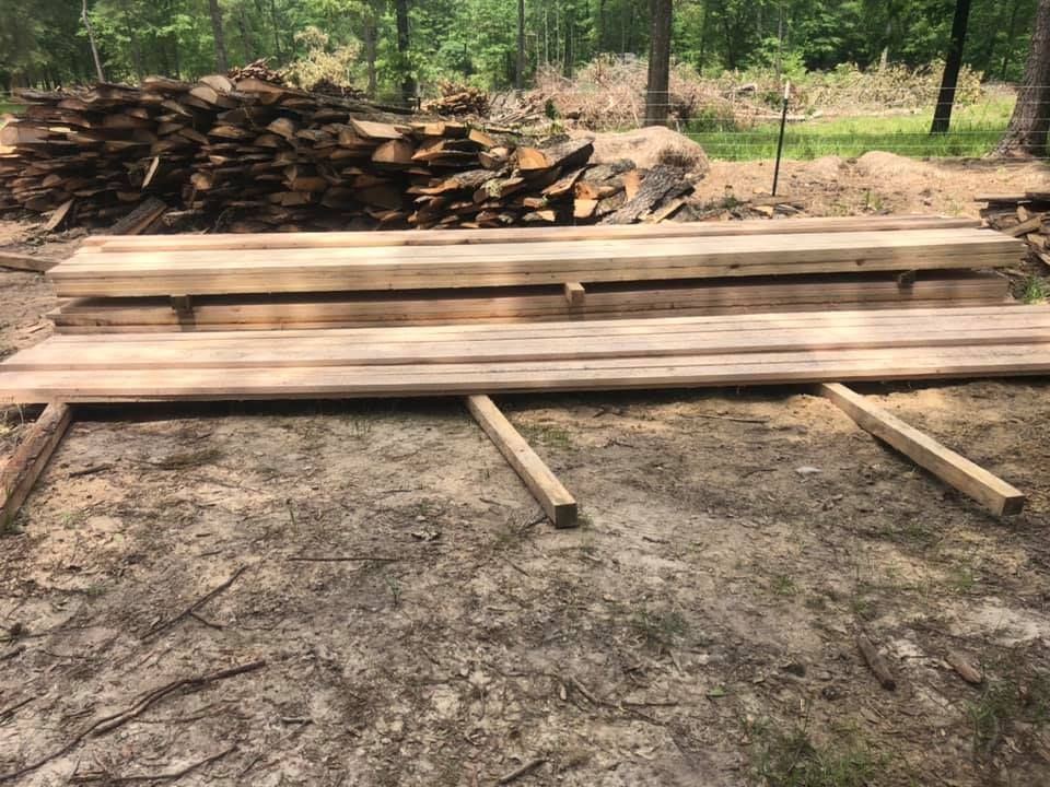 A pile of wood is sitting on the ground next to a pile of wood.