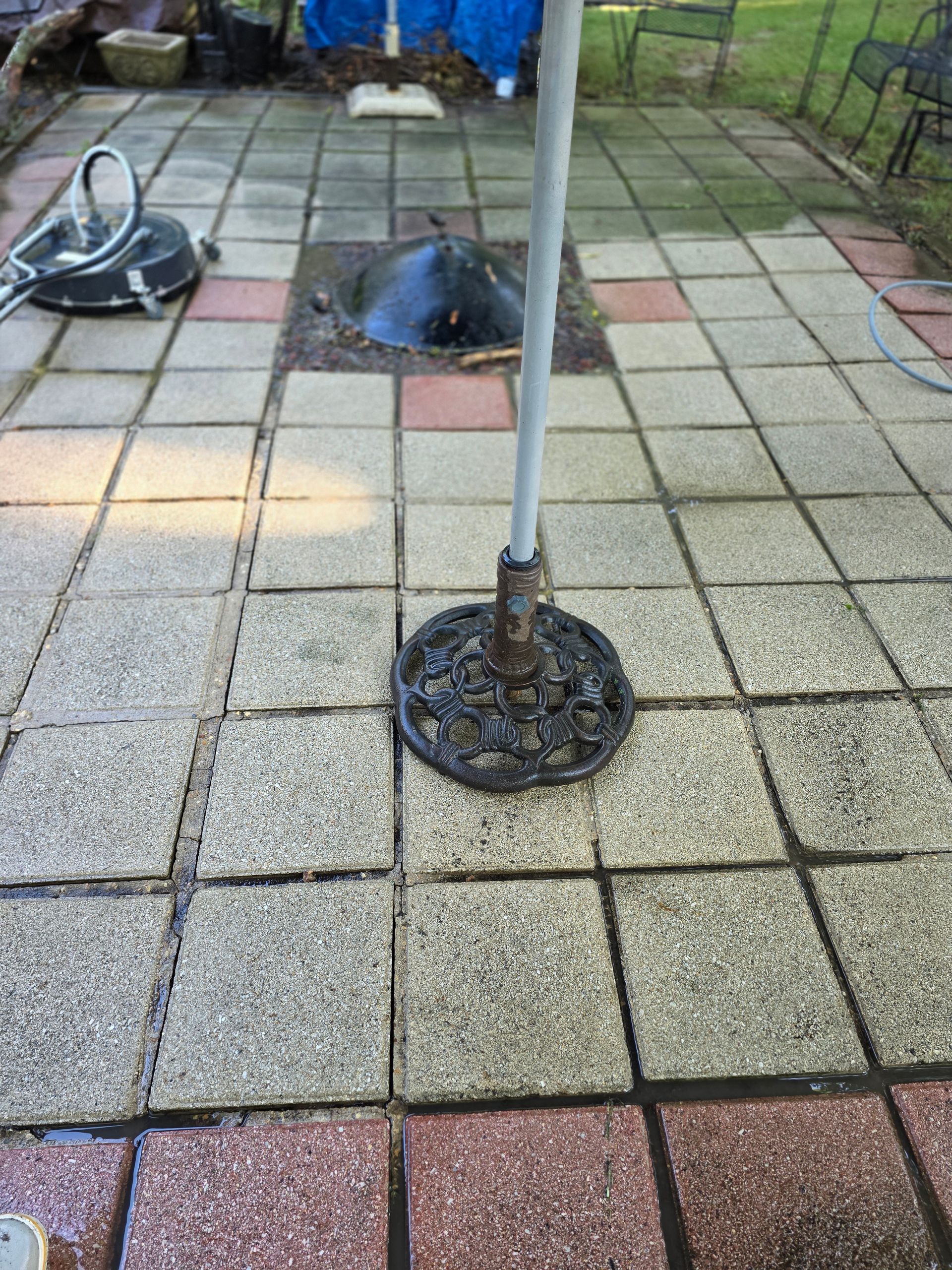 Stone retaining wall in front of a yard with trees, chairs, and a building in the background.