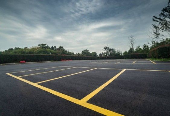 Empty parking lot with yellow lines, under a cloudy sky.