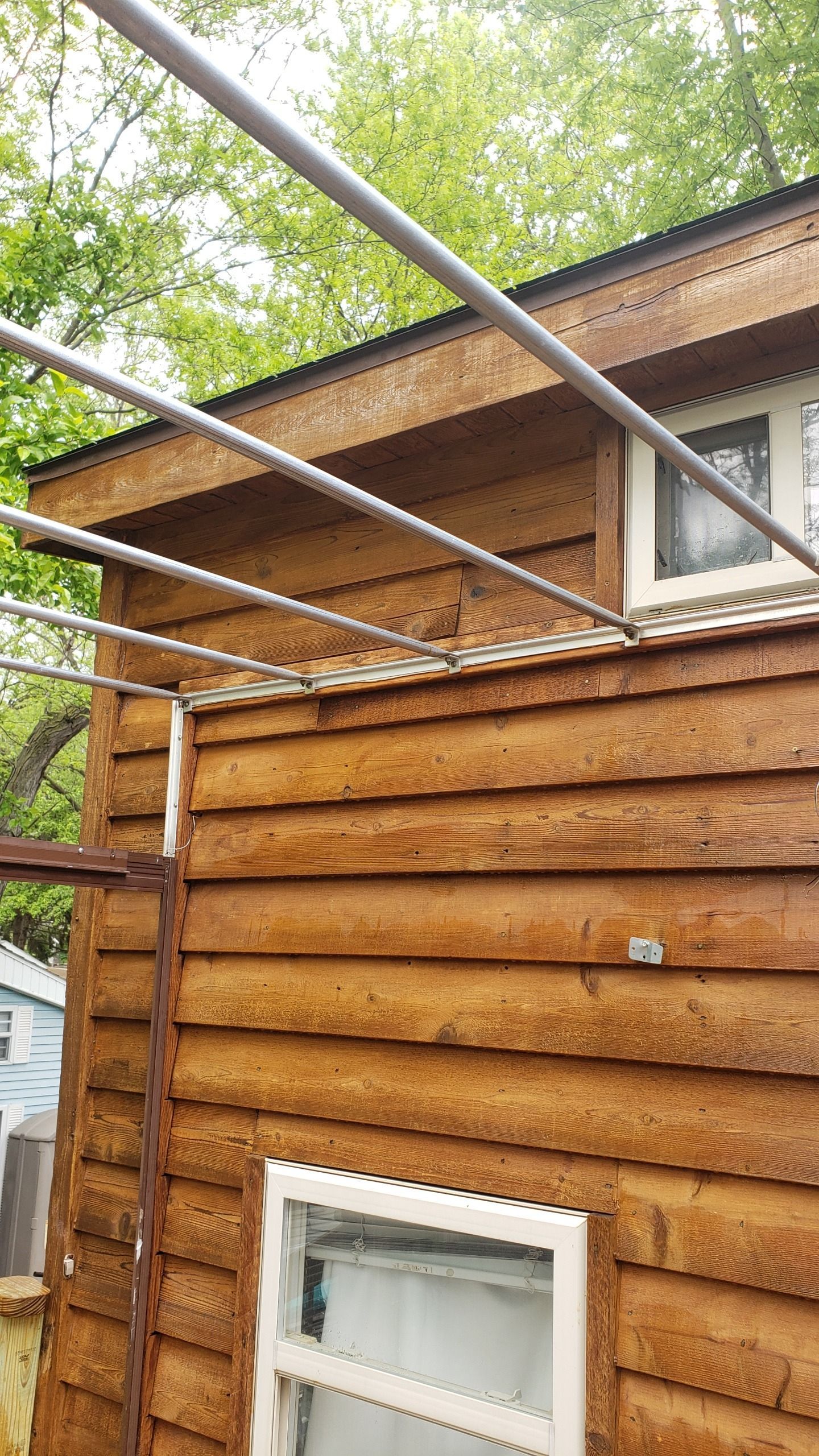 Wooden shed with metal pipes overhead, trees in the background.