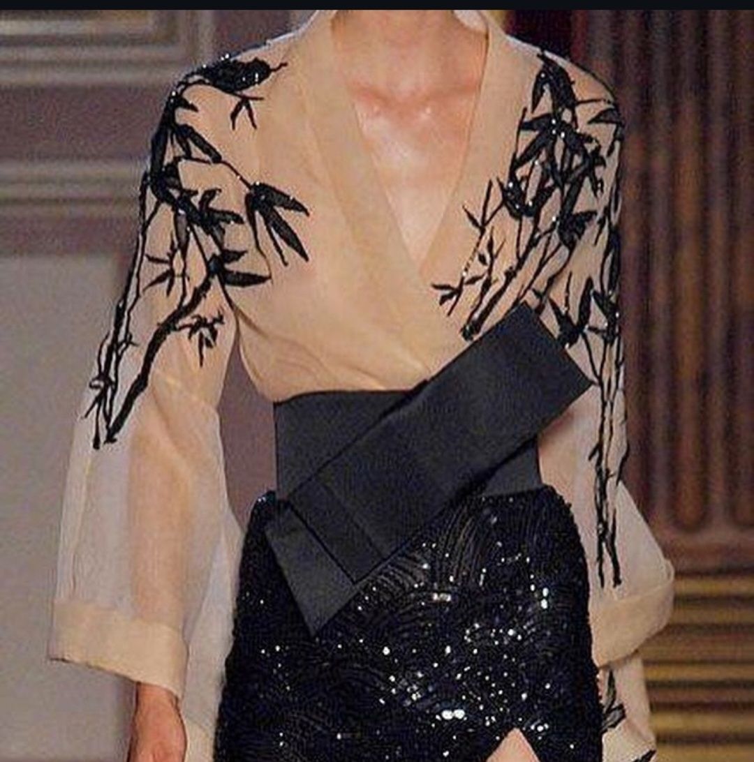 Una mujer que lleva gafas de sol y una chaqueta negra está parada en la oscuridad.