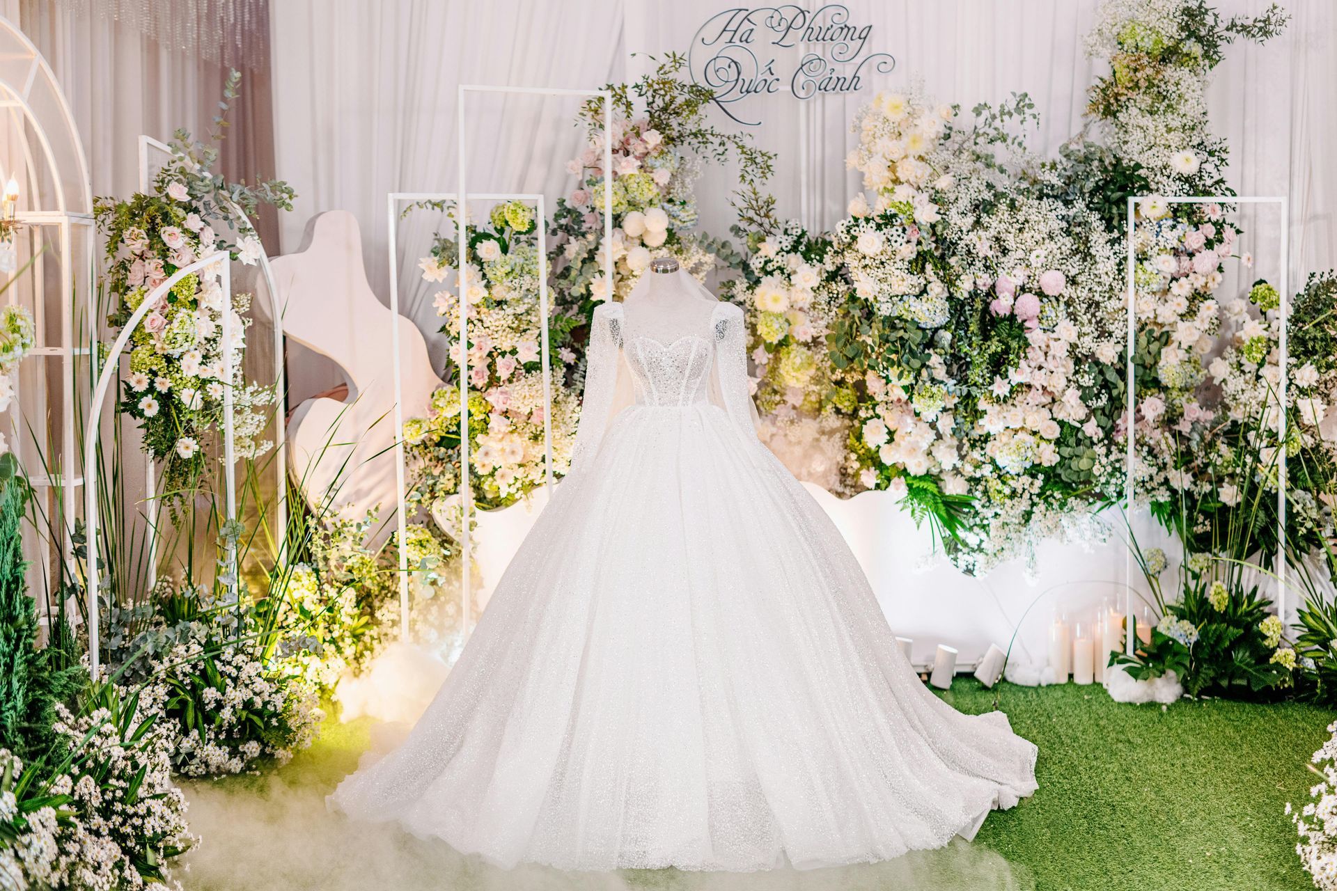 Un vestido de novia está sentado delante de una pared de flores.
