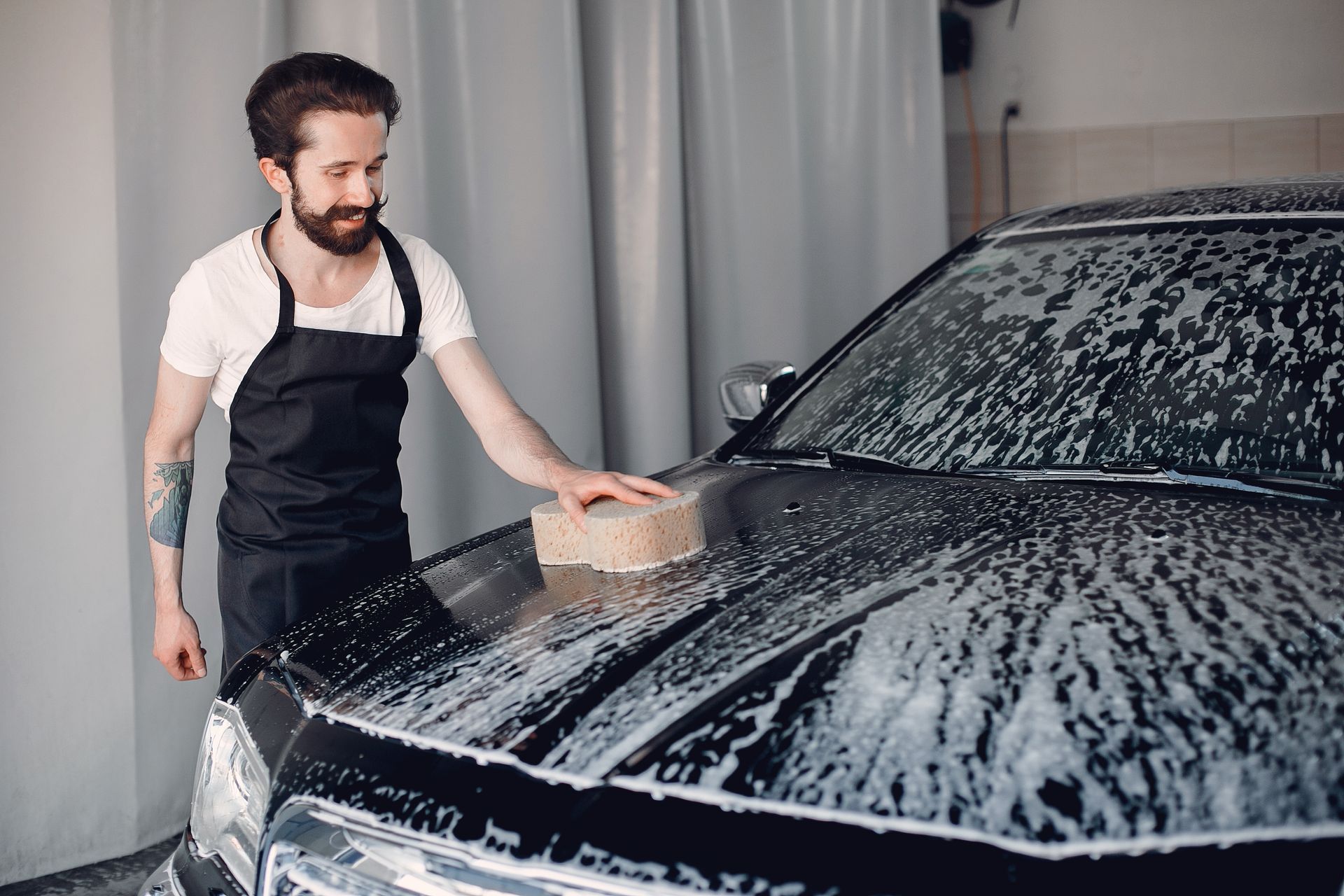 A man is washing a car with a sponge in a car wash.