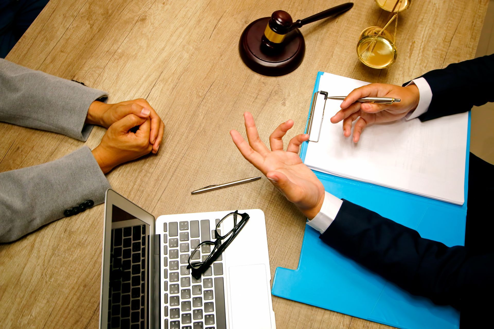 A man and a woman are sitting at a table with a laptop and a judge 's gavel.