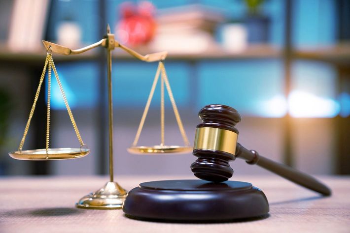 A wooden judge 's gavel and scales of justice on a wooden table.