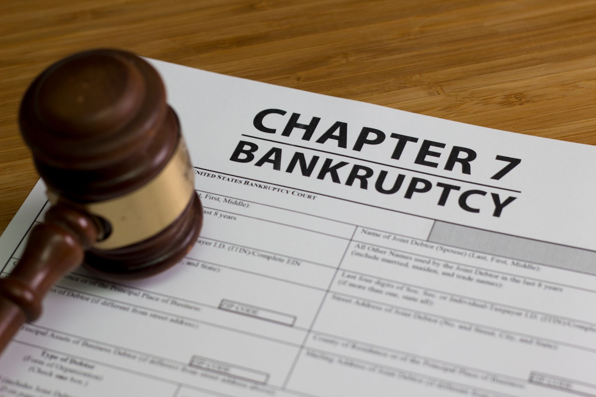 A wooden gavel is sitting on top of a chapter 7 bankruptcy form.