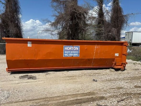 A yellow dumpster is full of garbage and has the word ford on it