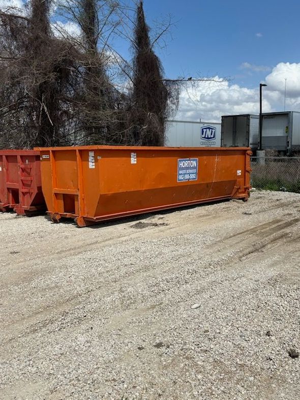 A large blue dumpster is sitting on the side of the road.