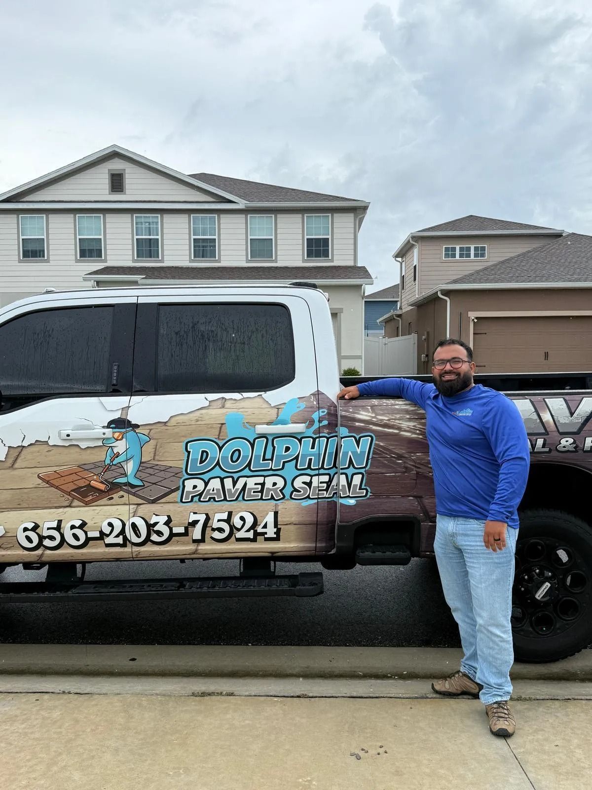 Man posing next to a company truck, with logo 