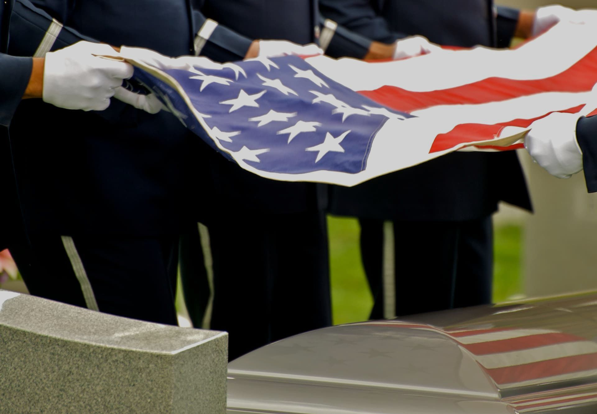 A man in a military uniform is holding an American flag in his hands.