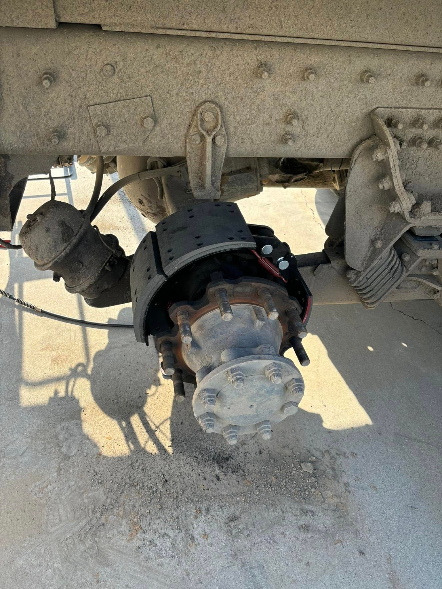 A side view of a semi-truck wheel assembly with the wheel removed, exposing the brake shoes, drum, and air brake canister.