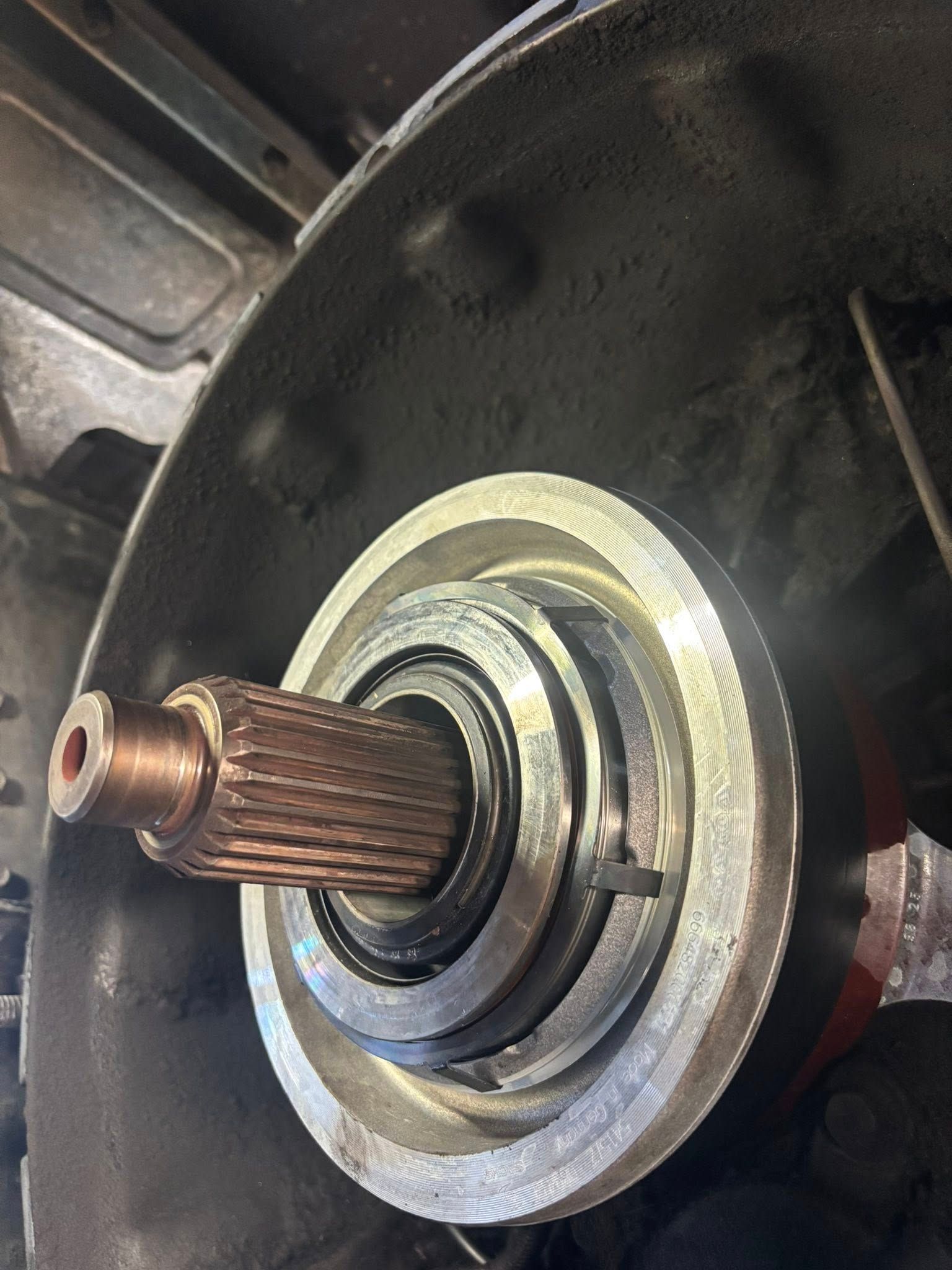 A close-up view looking into a vehicle's bell housing, showing a splined transmission input shaft and release bearing.