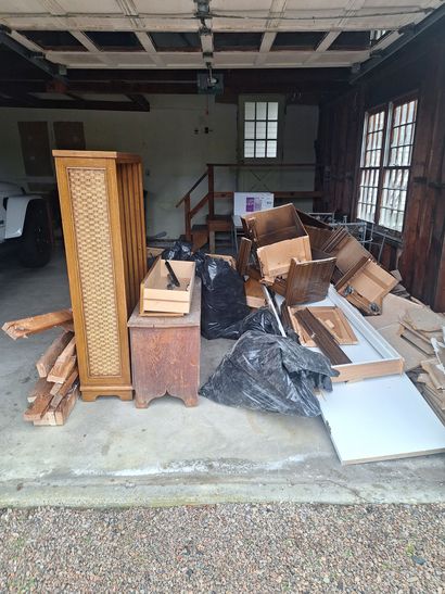 Curb-side pile of discarded furniture and boxes, including a mattress, sofas, and cardboard boxes, in front of a house.