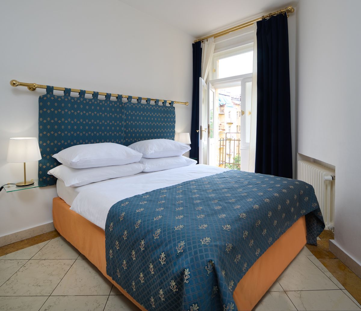 Camera da letto con copriletto e testiera color verde acqua, di fronte a una finestra con tende blu.