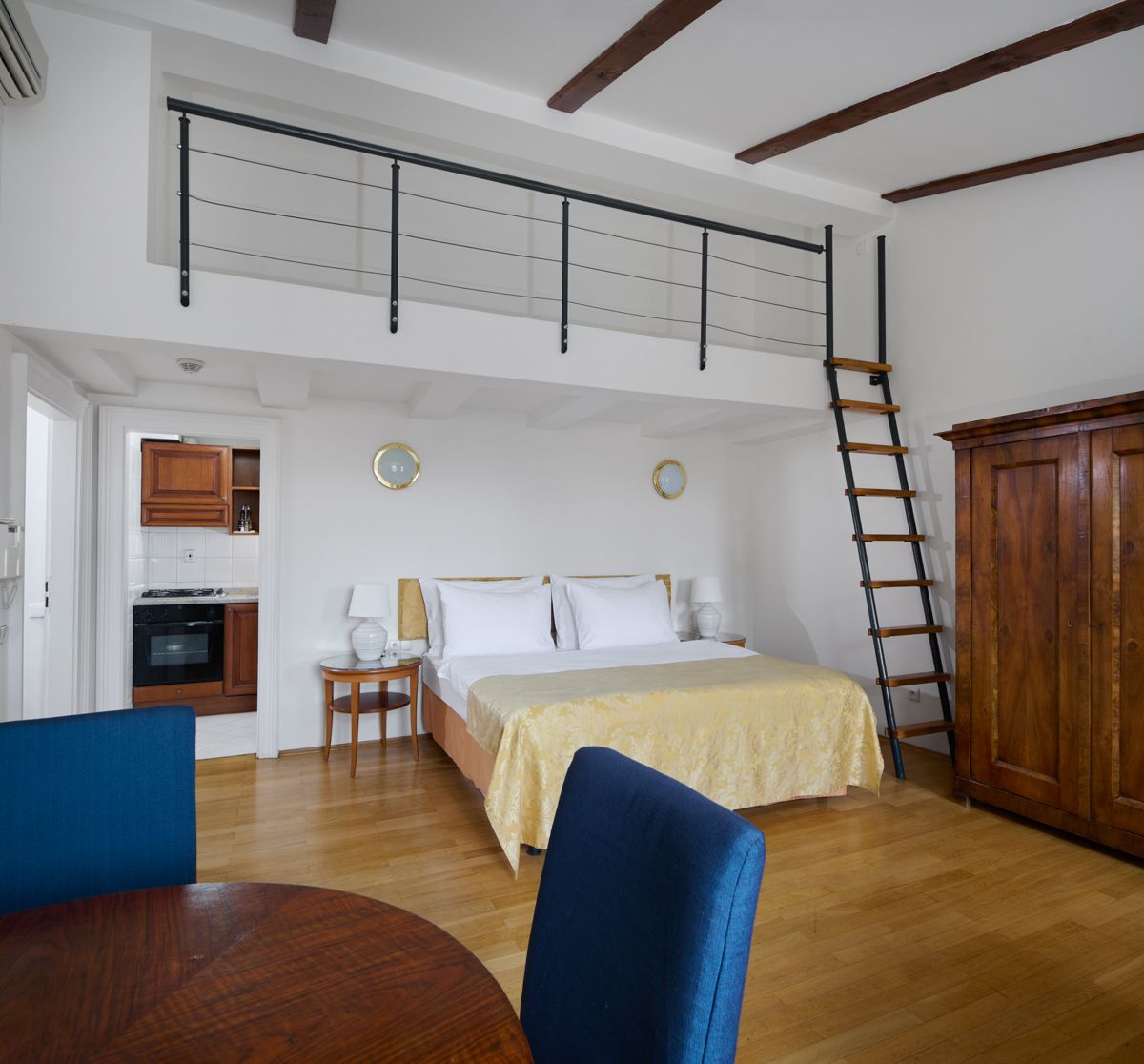 Camera da letto con letto a soppalco, pavimento in legno e piccolo angolo cottura.