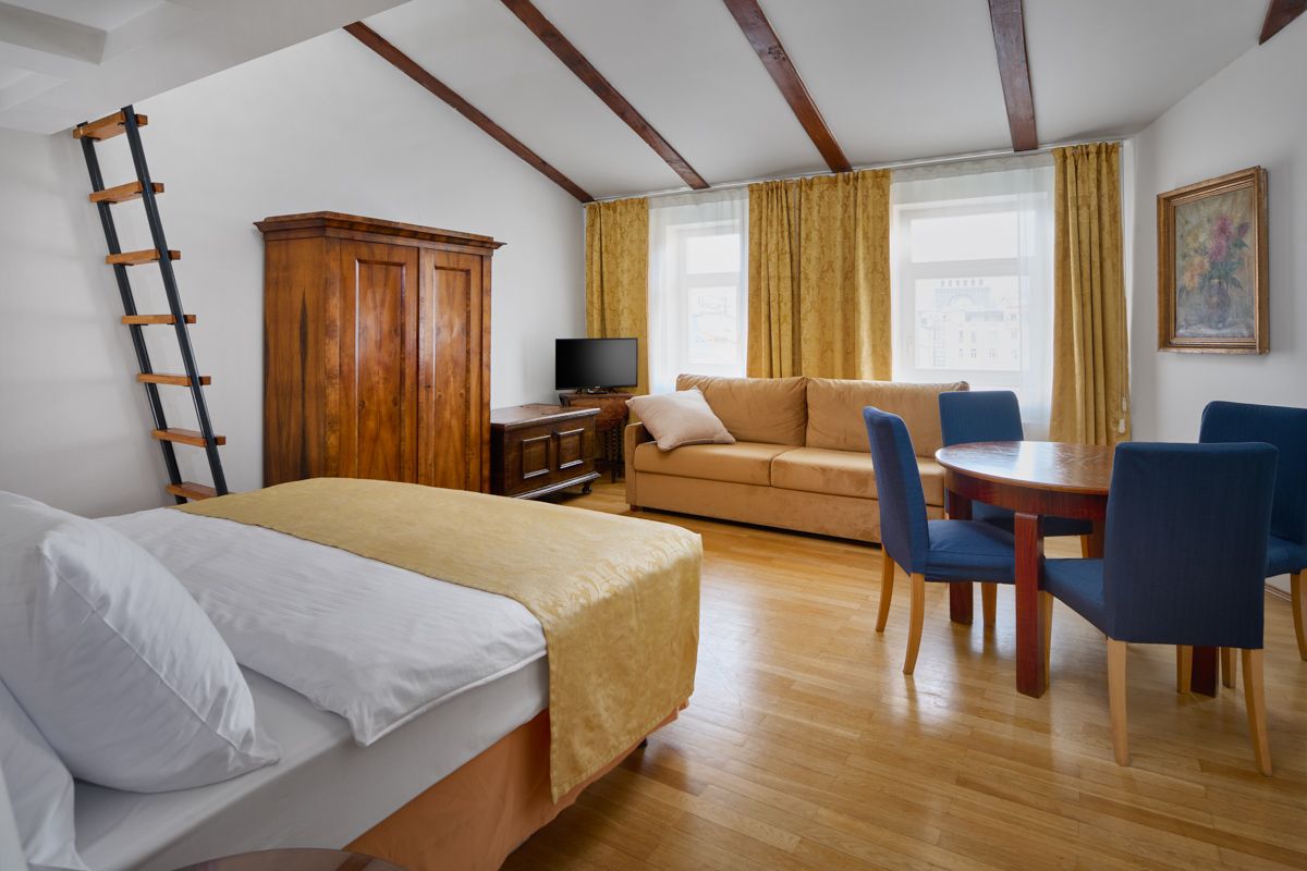 Cozy room with bed, sofa, dining table, wardrobe, and ladder to the loft, with yellow and wood tones.