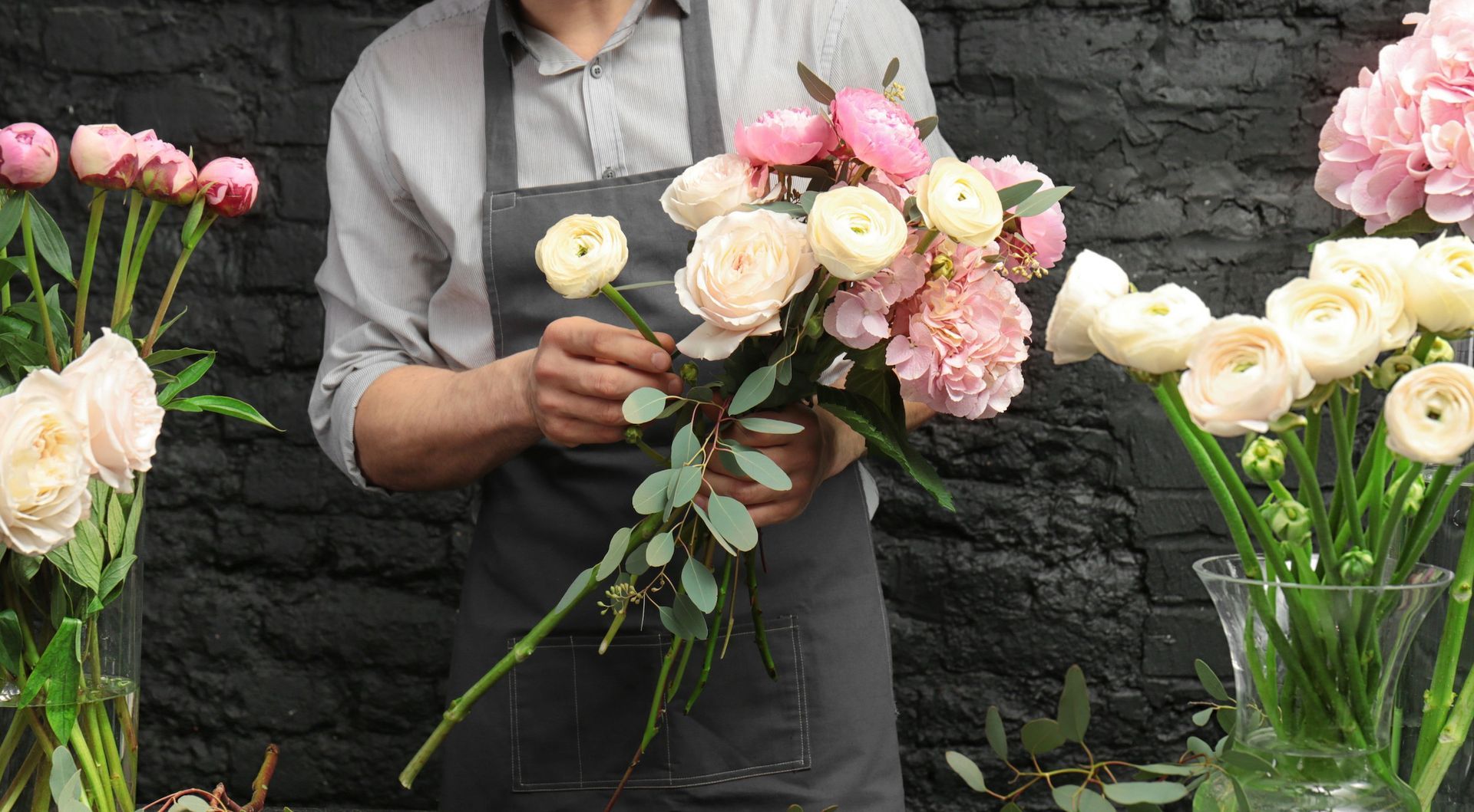 Fioraio che prepara un bouquet con fiori rosa e crema.