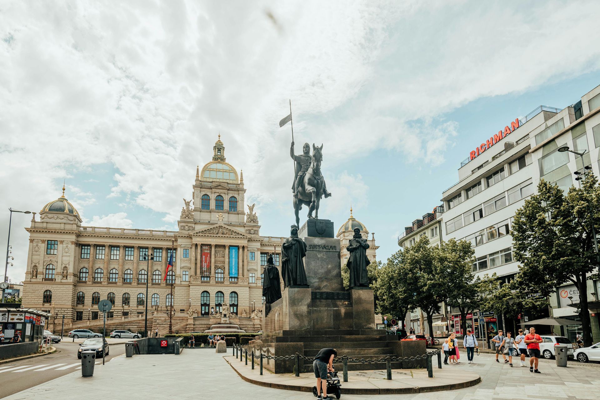 Street view of Prague, Czech Republic. Buildings line a pedestrian street, leading to a large building with a dome.