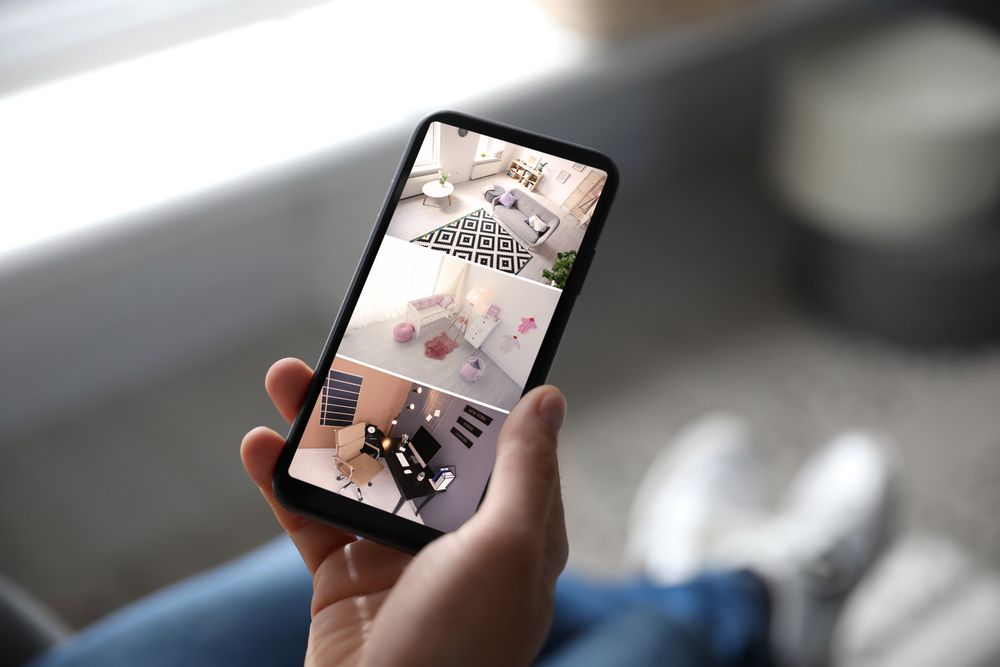 A person holds a smartphone displaying a collage of three different interior room designs.