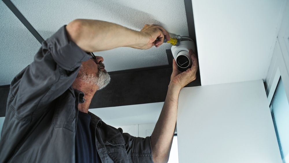 Woman in straw hat smiles, holding wine glass near a lake.