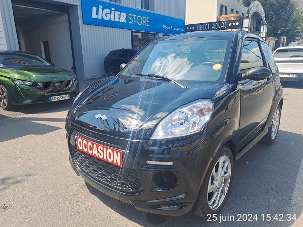 Une voiture noire est garée devant un concessionnaire automobile.