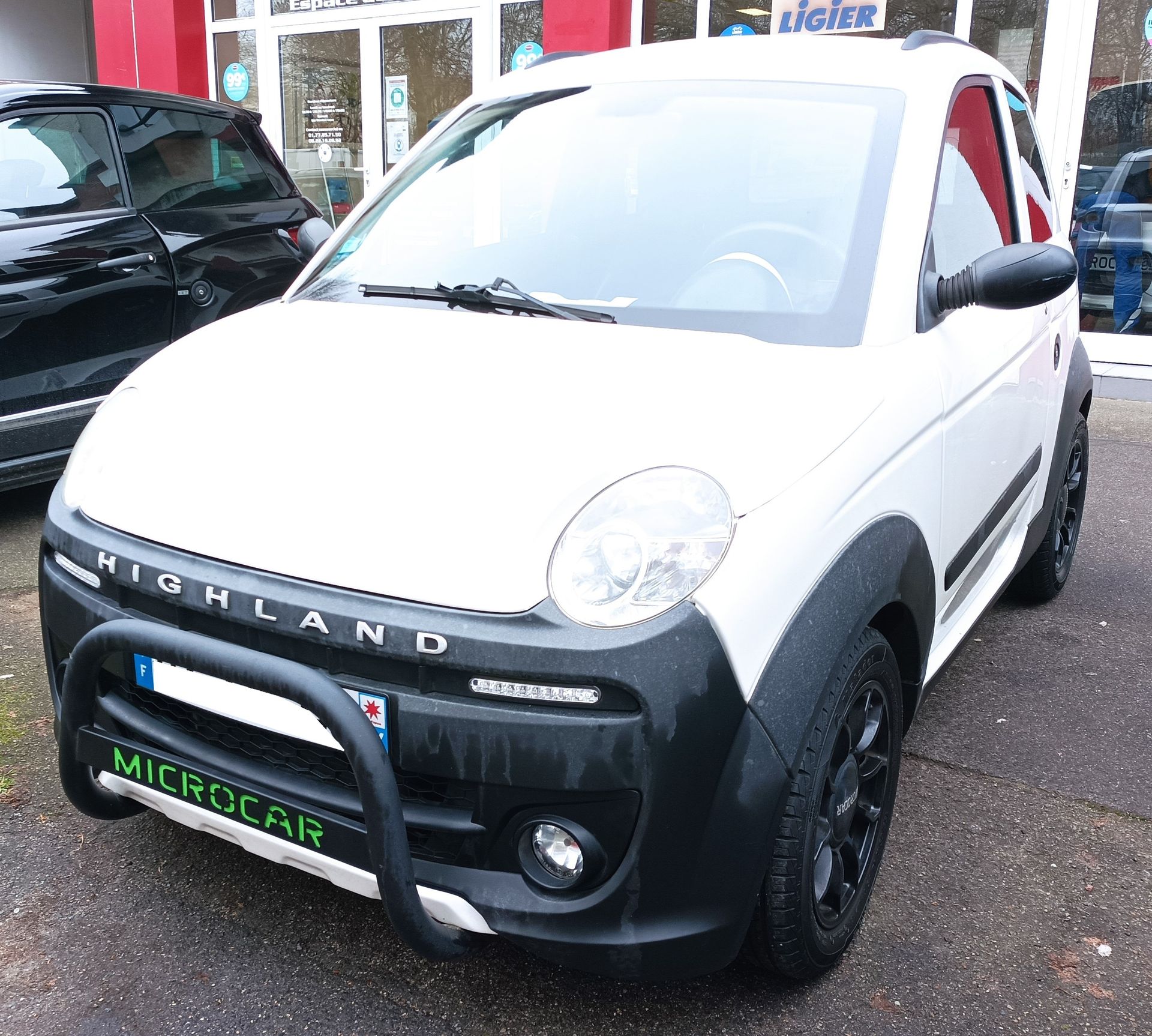 Une voiture blanche est garée devant un concessionnaire automobile.