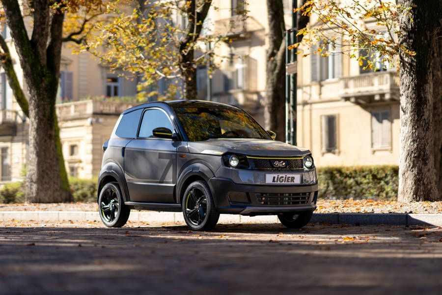 Une ligier grise est garée sur le bord de la route devant un bâtiment.