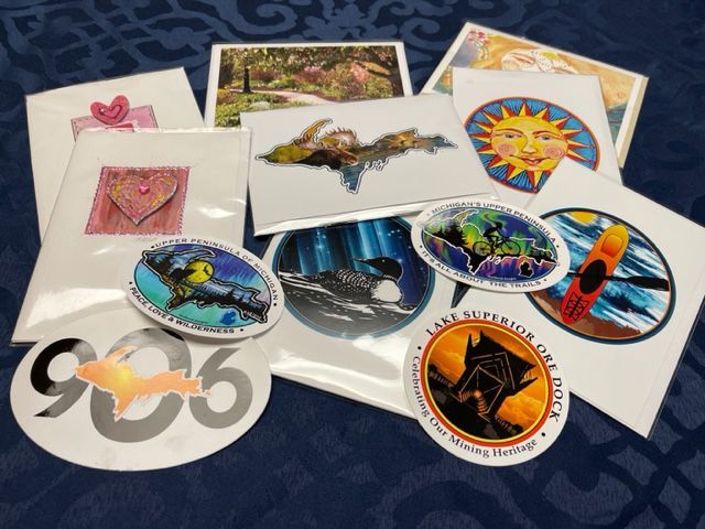 Cards and stickers with colorful nature-themed designs, including hearts, a sun, and Lake Superior imagery.