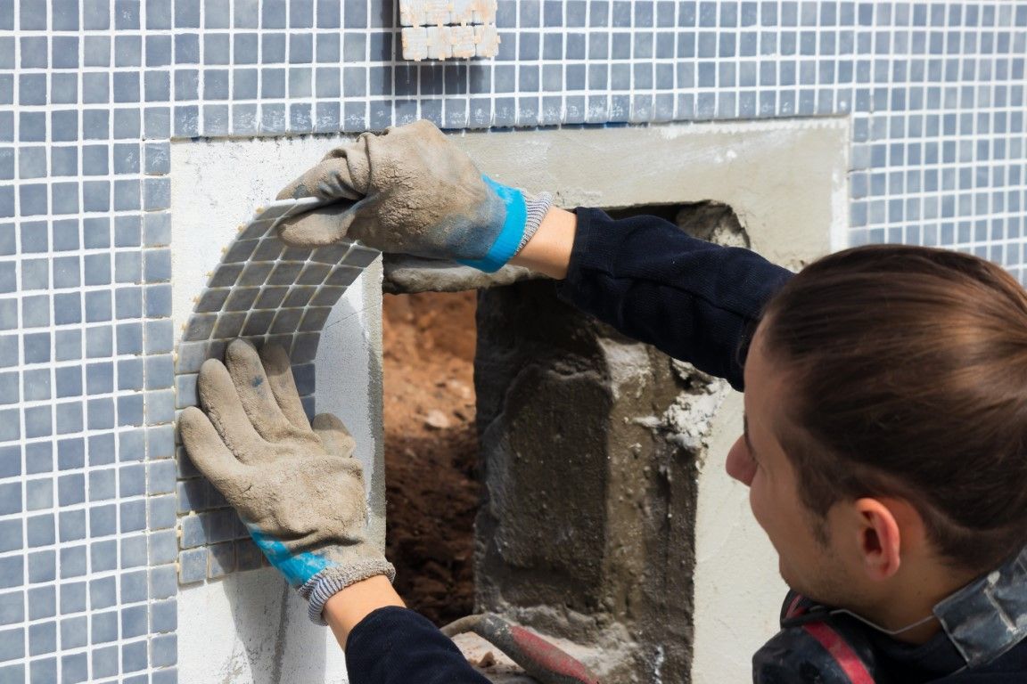 Man resurfacing a pool with blue tile