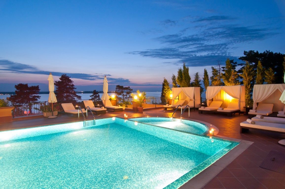 night time view of pool with ocean behind it