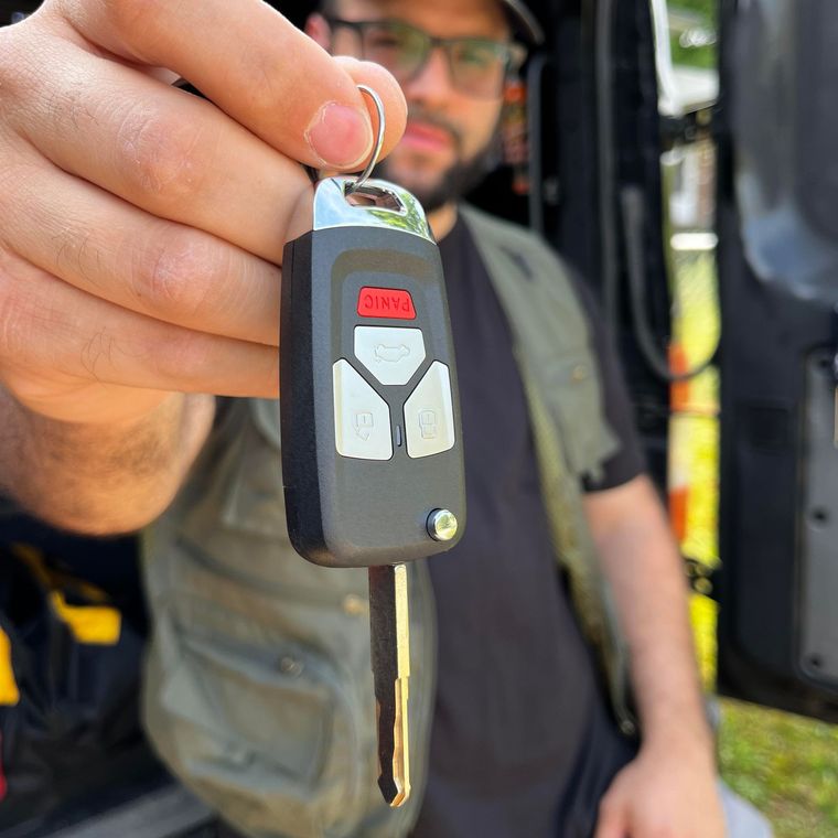 Close-up of a hand holding a car key fob with an extended metal key.