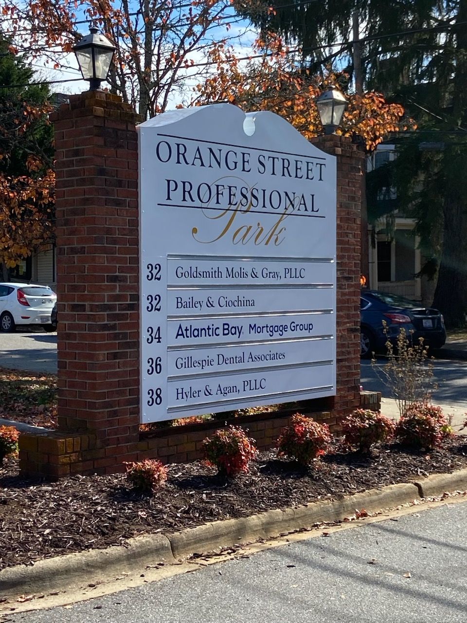 Sign for Orange Street Professional Park, with brick base and white sign panels listing businesses and addresses.