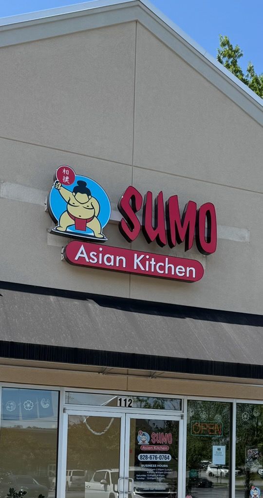 Sumo Asian Kitchen sign with a cartoon sumo wrestler. The sign is red and has a light tan building background.