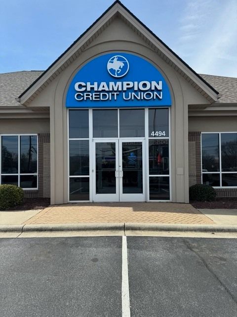 Champion Credit Union building with blue signage, tan facade, and large windows. The number 