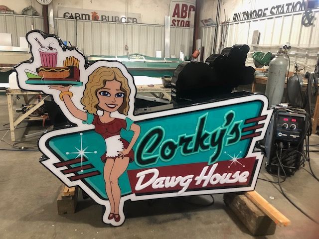 Corky's Dawg House sign featuring a cartoon waitress holding food, with retro teal and red design.