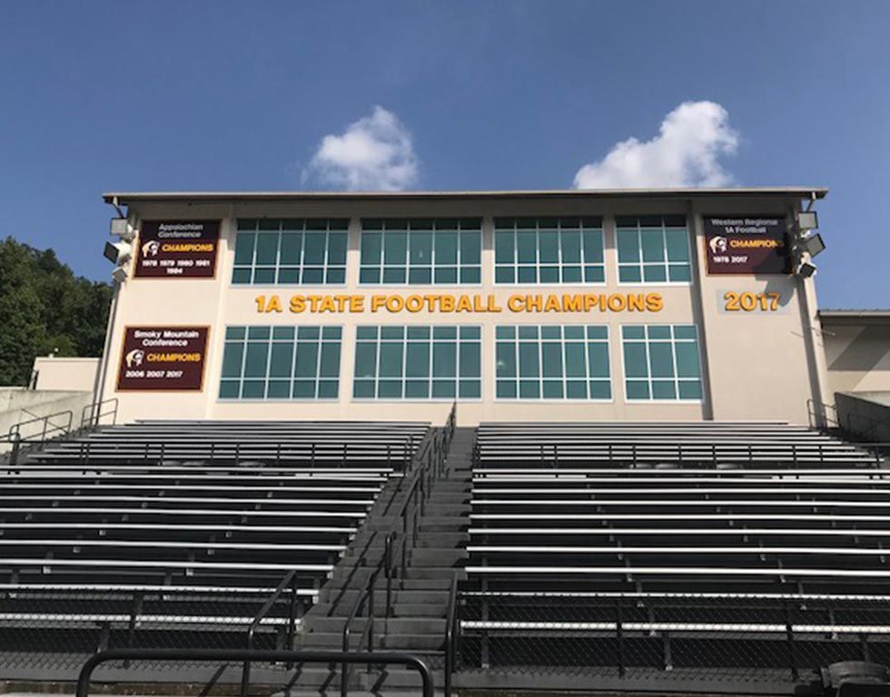 Empty stadium with bleachers facing a building that reads 