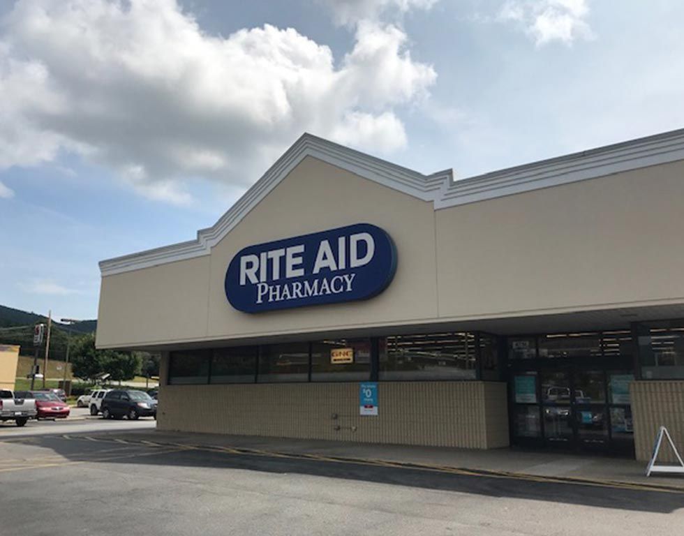Exterior view of a Rite Aid Pharmacy store with a blue and white sign under a partly cloudy sky.